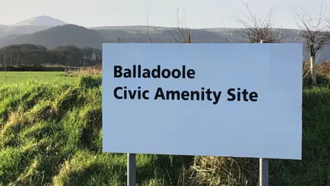 Sign of the Northern Civic Amenity Site in Balladoole. Mountains are seen behind.