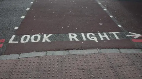 Stefanie Bringemeier/BBC The floor of a pedestrian crossing, with knobbly textured tiles on the edge of the footpath. There is also writing on the floor that says "look right".