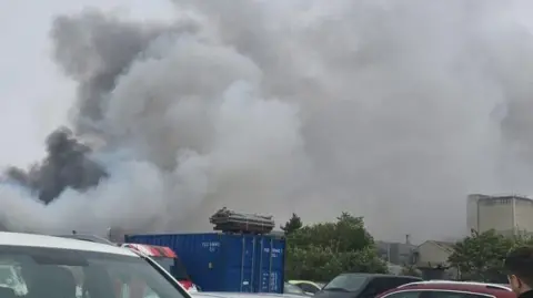 Jody Amber Thick smoke rises over a car park