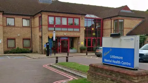Google Littlemore Mental Health Centre NHS sign in front of a large brick building.