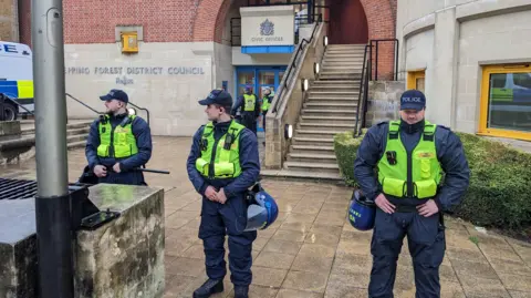 Pete Walker/BBC Three police officers are stood outside Epping Forest District Council offices