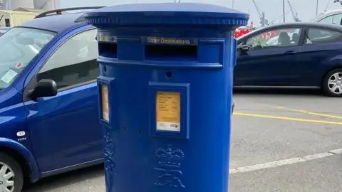 A blue post box with two letter slots. It is embossed with the crown and EIIR.