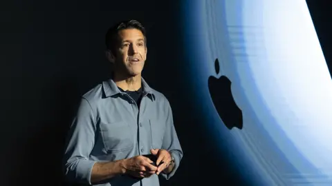 Getty Images John Ternus standing on stage in front of an Apple logo. He is wearing a grey shirt.