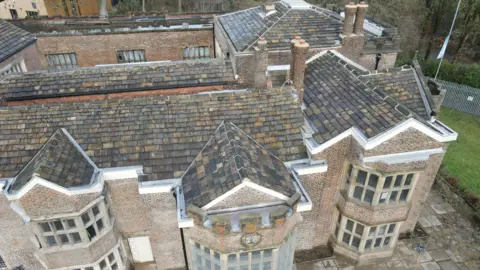 Hopwood Hall, a large historic stately home is seen from an aerial view of the large brick building