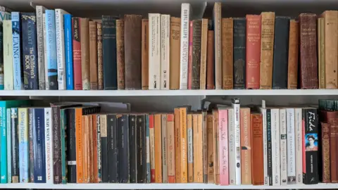 Getty Images A variety of books on two white shelves.