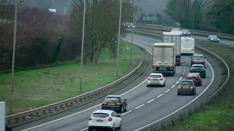 A general view of the A1 near Stibbington. Vehicles travel on each side of the carriageway on a cloudy day. Grass verges can be seen each side of the carriageway.