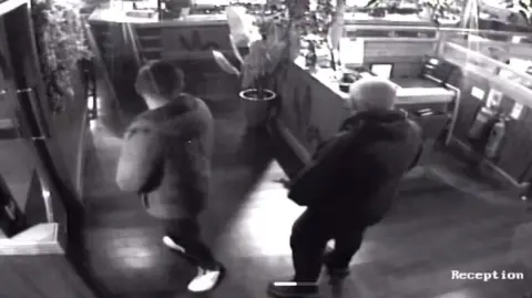 Welsh House CCTV footage of the inside of their restaurant with the back of two men in forefront