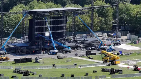 Getty Images An aerial view of the infrastructure and stage being constructed in Heaton Park. Various plant and machinery is working in the foreground, with barriers in place on the grass where fans will stand or sit.