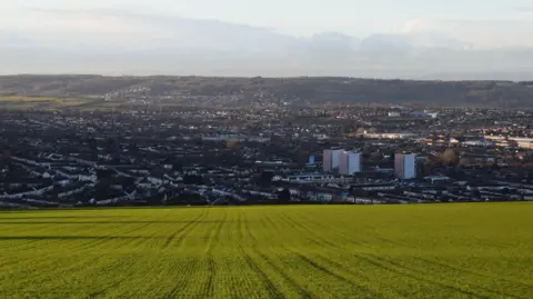 Getty Images A large green hill overlooking the city of Bristol, with residential streets and tower blocks visible