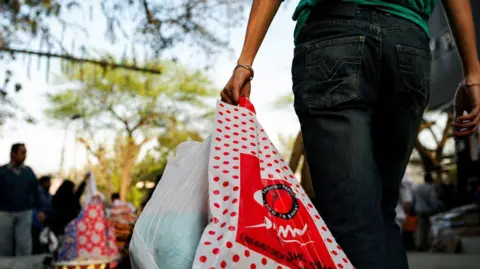 An Indian man carries goods in a plastic bag at a crowded market in New Delhi on February 17, 2009. The Indian capital, passed a law earlier this year banning sale and use of plastic bags at shopping areas, eating joints, hotels and hospitals. India in recent years has made moves and a conscious effort to eliminate the use of plastic bags with some shops using paper bags instead. AFP PHOTO/ Prakash SINGH (Photo credit should read PRAKASH SINGH/AFP via Getty Images)