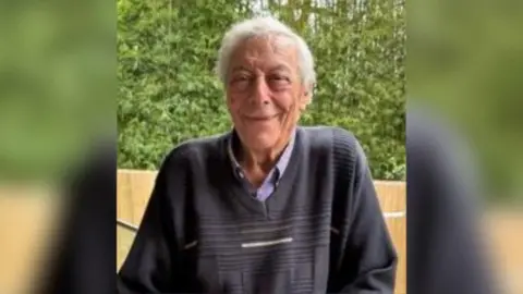 NSW Police An elderly man with grey hair and wearing a dark blue jumper smiles at the camera