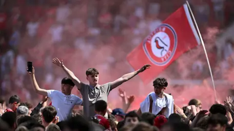 Getty Images Bristol City fans, some on other people's shoulders, cheer and wave after their team clinched a place in the Championship play-offs