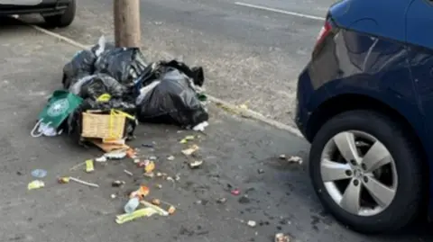 Kieran Hunt A pile of rubbish left between two cars on a residential road.