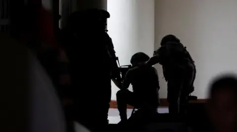 Military personnel in camouflage fatigues enter the Senate building where Philippine Senator Ronald "Bato" dela Rosa, the chief enforcer of former president Rodrigo Duterte's drug war, at the Senate, is under protective custody amid an International Criminal Court warrant, as more than a dozen gunshots were heard at the Philippine Senate on Wednesday, and people were told to run for cover, according to a Reuters witness, in Pasay City, Metro Manila, Philippines, May 13, 2026. REUTERS/Eloisa Lopez
