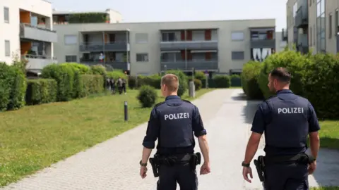 Two police officers walking towards a low-rise building where the 21-year-old suspect lived. 