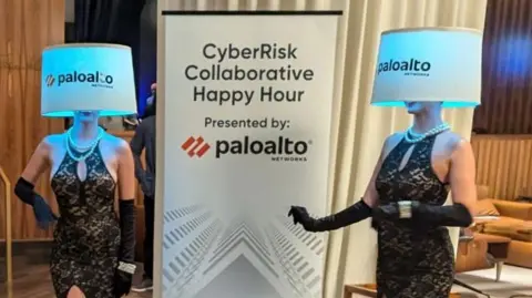 Sean Duroviesky (LinkedIn) Two women in dresses pose with Palo Alto-branded lampshades covering their faces