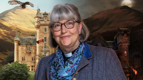 BBC/STUDIO LAMBERT A smiling woman with short grey hair and a fringe, glasses and a grey jacket, with a religious dog collar hidden behind a blue scarf.