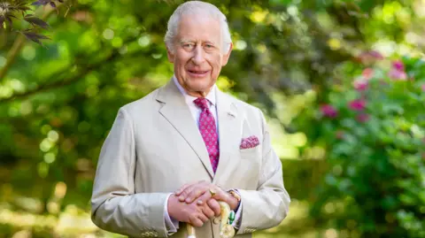 King Charles in a summer suit holds a shepherd's crook