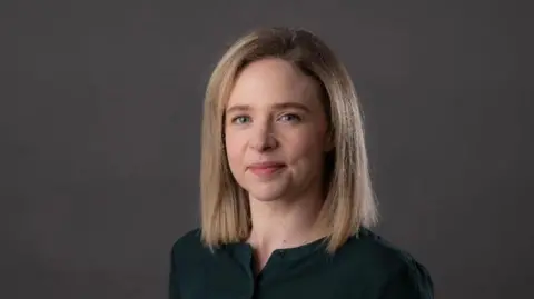 Queen's University Professor Laura McGowan, facing the camera, with blonde hair and dark top.