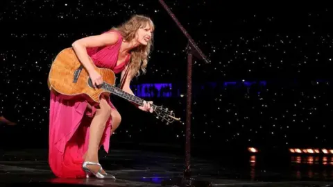 Getty  Taylor Swift performing with a guitar