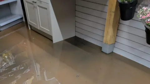 Inside the Ewyas Harold Village Shop and Post Office, murky brown water is visible