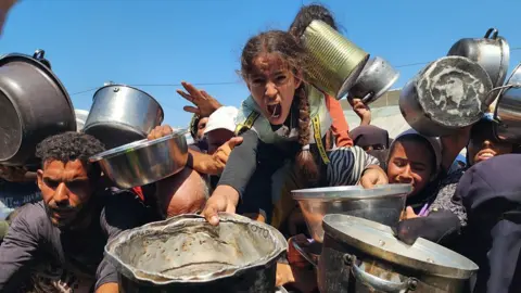 Getty Images Palestinians struggling with hunger crowd around as a charity distributes food in the Al-Mawasi area of Khan Yunis, Gaza amid ongoing Israeli restrictions blocking humanitarian aid from reaching Gaza, on 24 July 2025. 