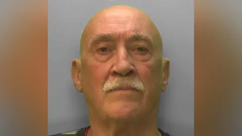 A bald man. He has a grey mustache. 