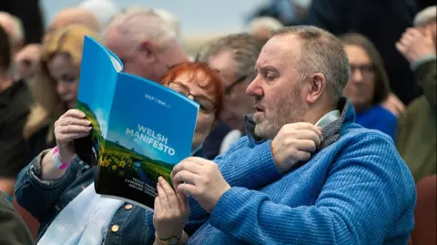 Getty Images A man and a woman in the audience of the event read the Reform manifesto