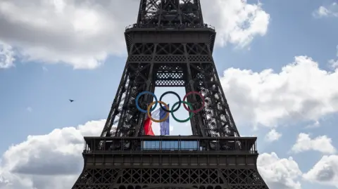 Getty Images Olympic rings and a French flag on the Eiffel Tower in Paris