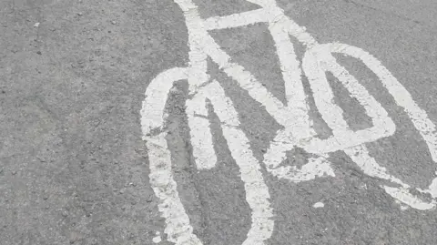 A cycle route road sign painted in white paint onto a road.