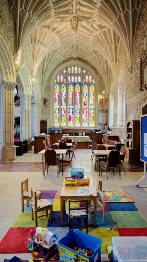 Ottery St Mary Church A view of Ottery St Mary Church showing a space for people to sit and children to play inside the church and the grand arches of the building above. 