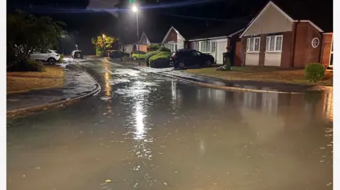 A flooded street at night, with water in the road