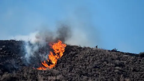 Fire and smoke on a hilltop as part of the Laguna Fire near California State University Channel Islands. 