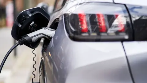 Rear view of an electric charger plugged into a silver car 