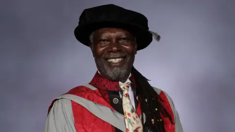 UWE Bristol Levi Roots. He is pictured wearing a graduation cap and gown. He is smiling at the camera. 