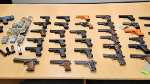 West Yorkshire Police A selection of guns laid out on a table with ammunition. 
