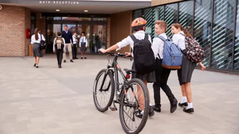 Getty Images School student some with bikes arriving at a moder school building