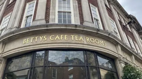 A gold sign for Bettys Cafe and Tea Rooms above glass windows