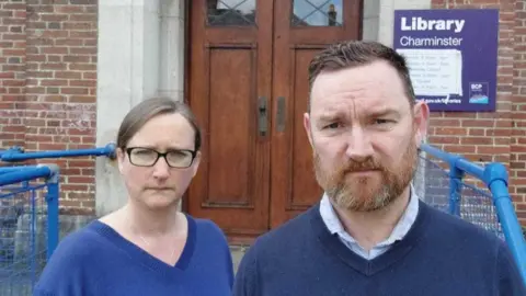 Green Party councillors Kate Salmon (left) and Alasdair Keddie wear disgruntled expressions as they stand outside the door of Charminster Library.