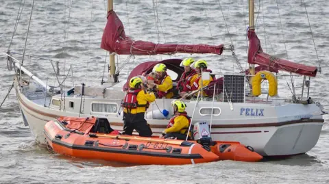 Stranraer RNLI A lifeboat crew next to a boat retrieving a dog from the vessel