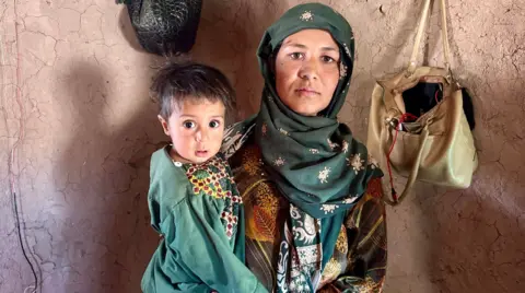 Aakri Thear / BBC Hanida, con un cidré serio, está envuelto alrededor de la cabeza, atrapando a Rafiullah que tiene cabello oscuro, ojos grandes y con el verde verde. Se paran frente a lo que se ven tan pared