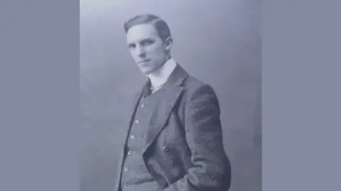 William Parr, with his hand in his double-breasted suit and shirt and tie, looks at the camera in this black and white photo