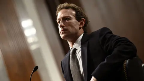 Meta CEO Mark Zuckerberg speaks at a hearing. He has a neutral expression on his face. 