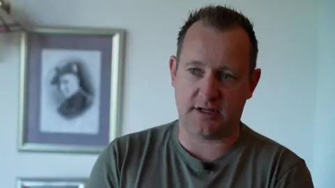 Rob Vdhoven has short dark hair and is wearing a green t-shirt
