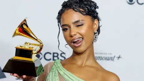 Getty Images Tyla holding her Grammy Award in Februay 2024 winks for photographers