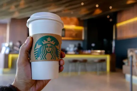 Hand holding a coffee cup in a Starbucks coffee shop