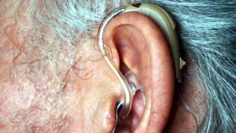 Side view of the ear of a man wearing a hearing aid