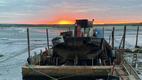 A burnt out boat on mud flats