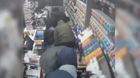 CCTV image of men raiding a shop.