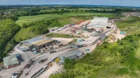 BBC An aerial view of Ashcroft Quarry shows a site surrounded by green countryside. Several buildings are connected by dirt roads.